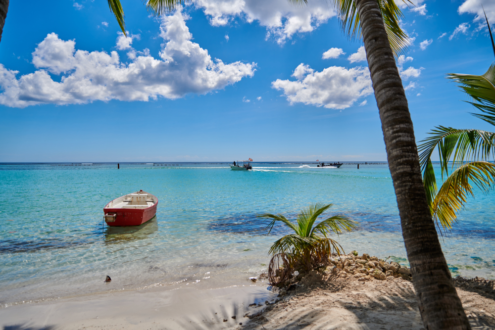 The beach of Boca Chica in the Dominican Republic with a beautiful blue sky and red row boat. 