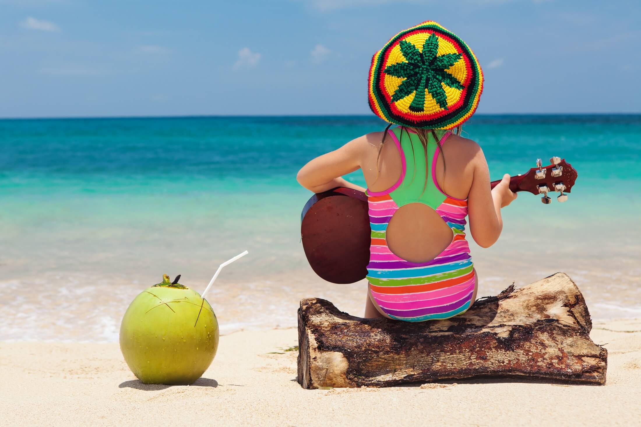 Małe szczęśliwe dziecko w rastaman kapelusz baw się dobrze, grać muzykę reggae na hawajskiej gitarze, cieszyć się relaks na plaży ocean. Dzieci zdrowy styl życia. Podróże, aktywność rodzinna na na tropikalnej wyspie wakacje