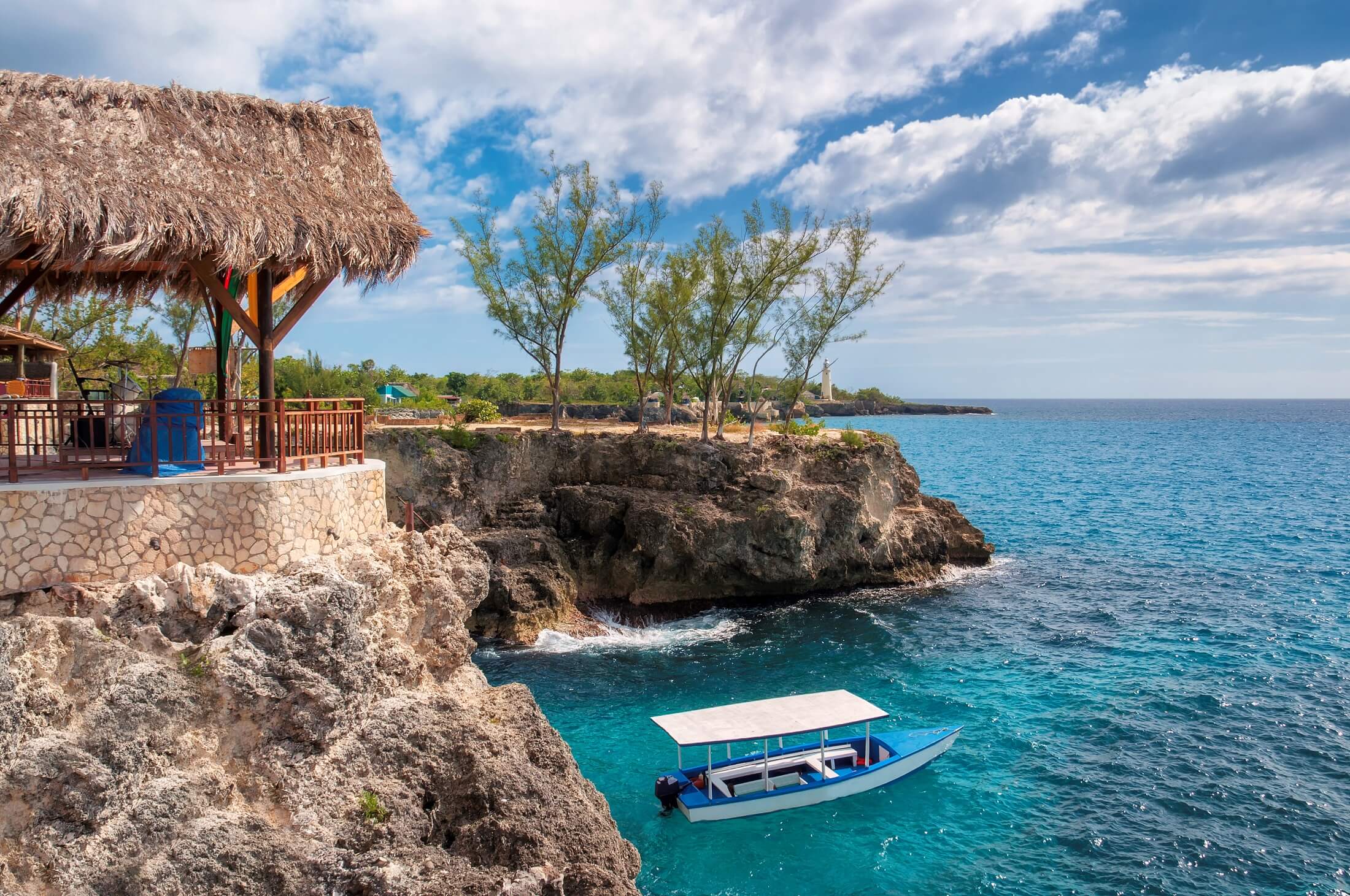 Negril, Jamajka, Karaibska skalista plaża z turkusową wodą, turyści łodzi i latarni morskiej.