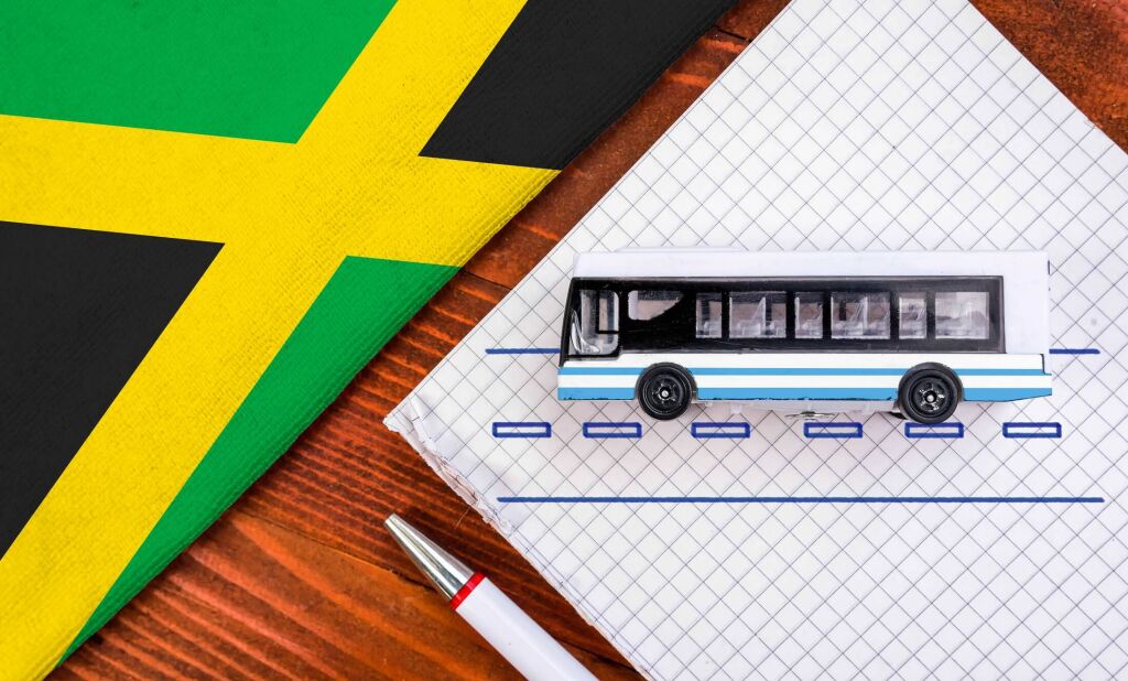 Toy bus and flag of Jamaica. Travel concept