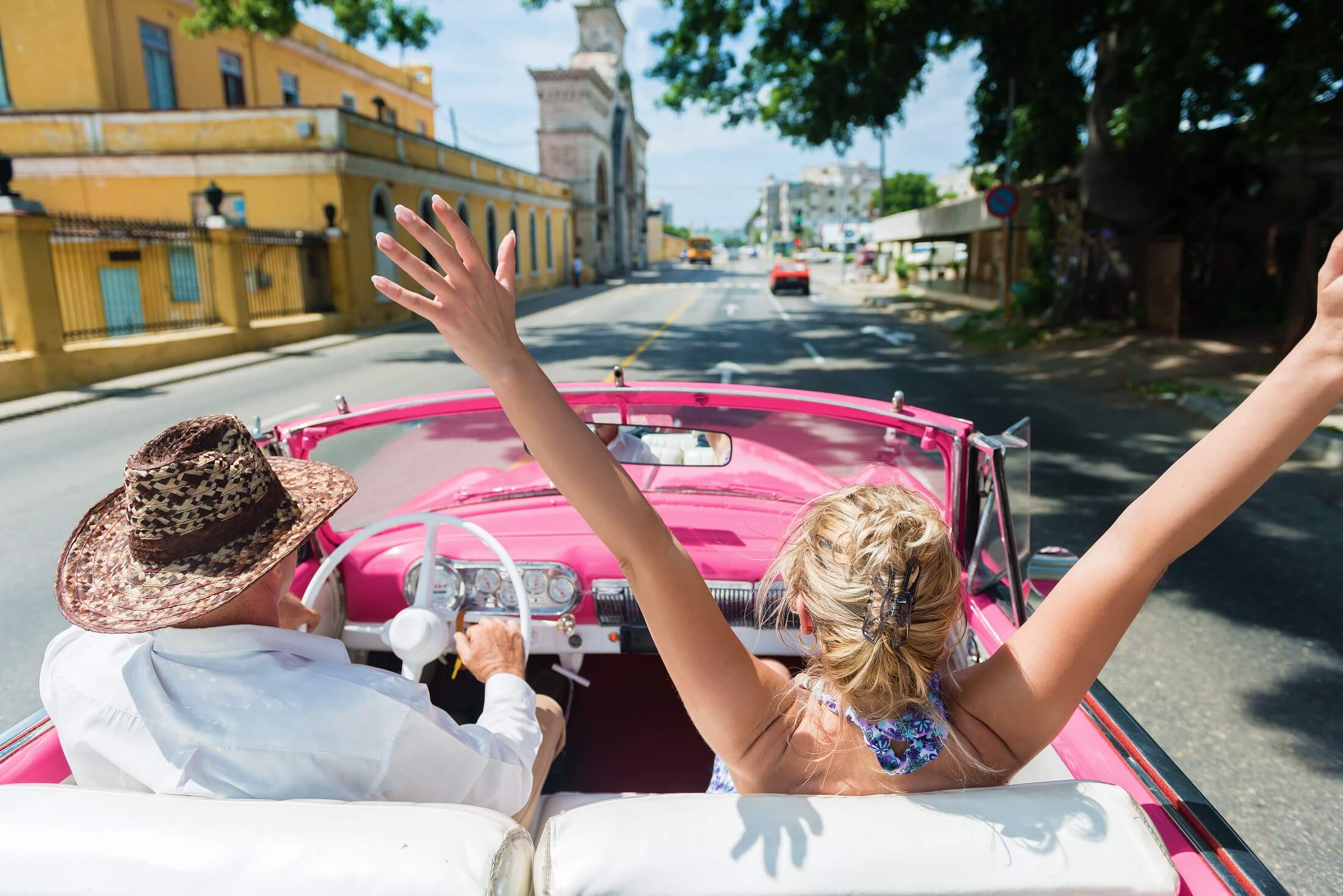 Widok z tyłu szczęśliwych przyjaciół cieszących się w kabriolecie jazdy przez Hawanę