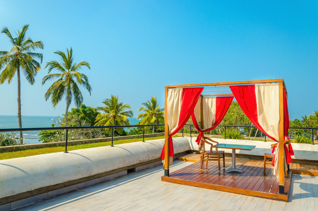 Pergola with tables and chairs, red curtains on luxury hotel  on a sunny day
