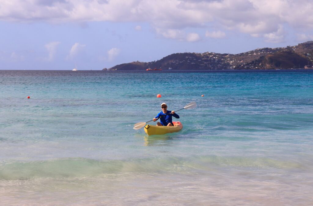 Tourist man kayaking in Grand Anse Beach, the most famous beach in Grenada, West Indies, Caribbean island.