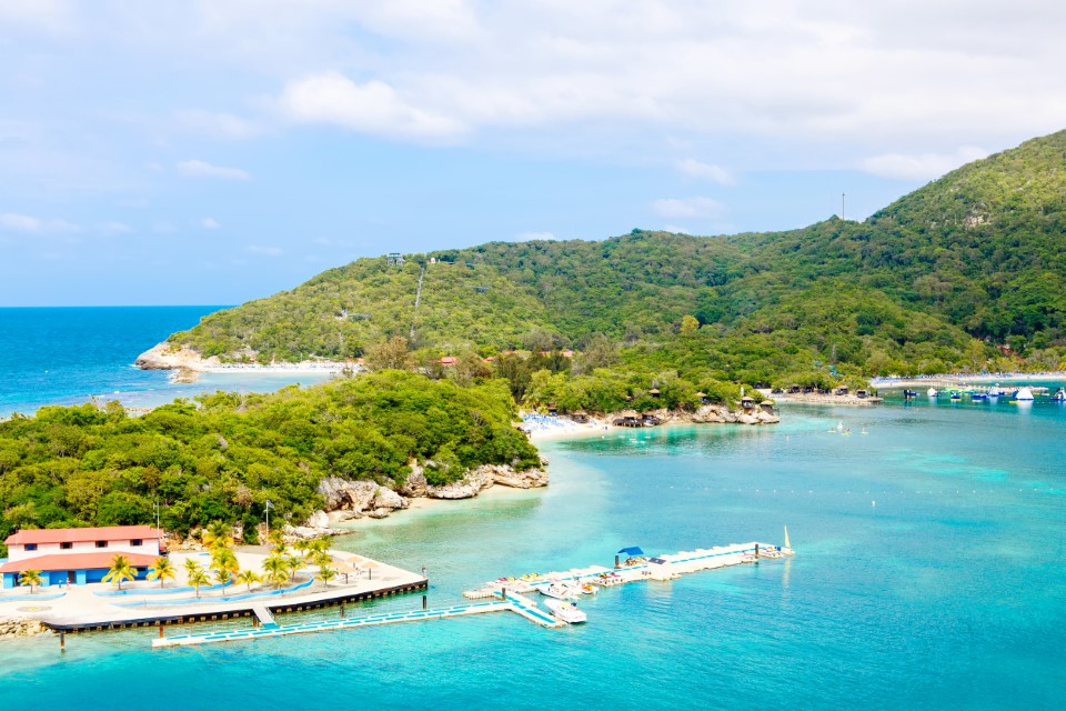 Plaża i tropikalny kurort, Wyspa Labadee, Haiti. Egzotyczna dzika plaża z palmami i drzewami kokosowymi przeciwko błękitnemu niebu i lazurowym wodom
