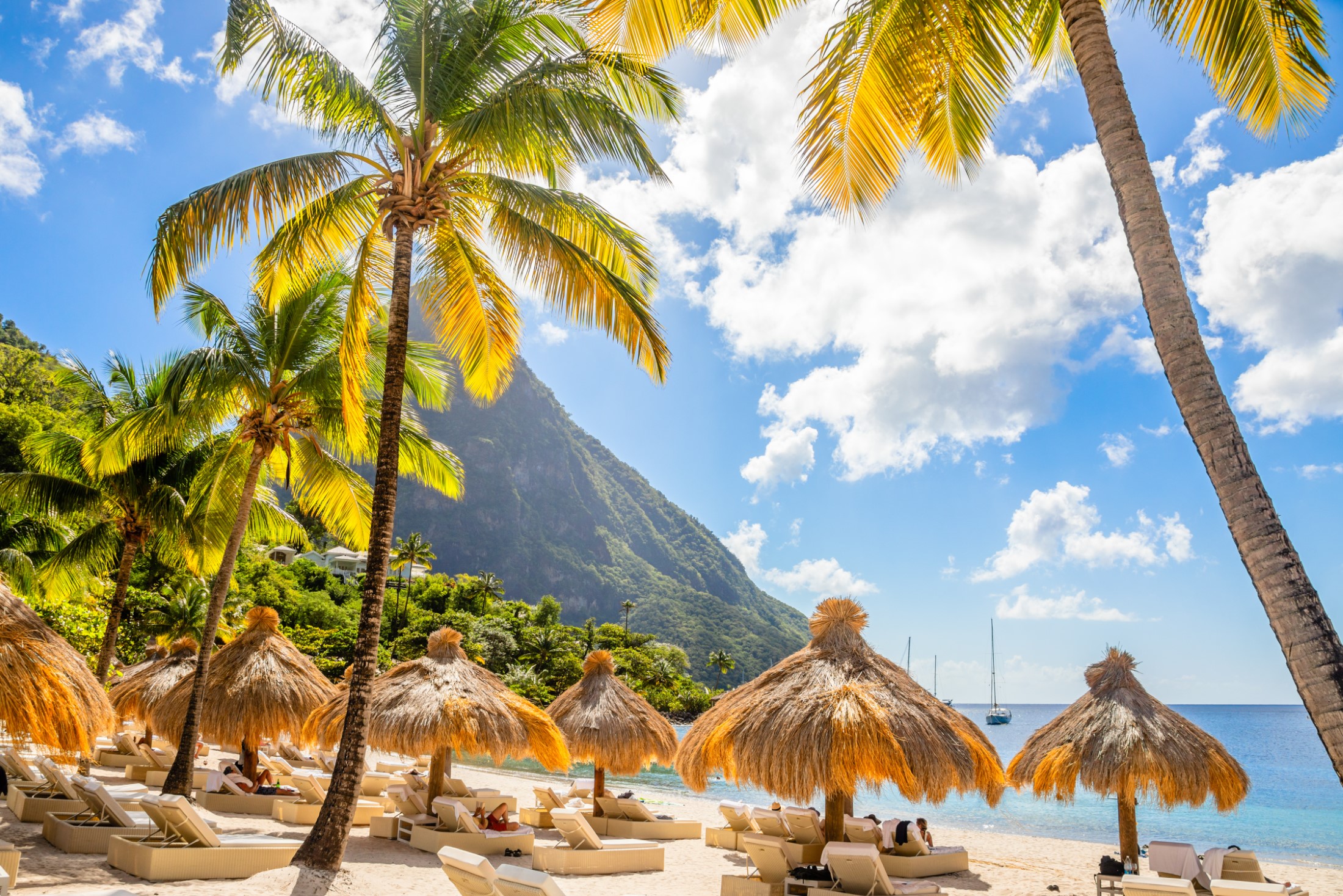 Karaibska plaża z palmami i słomianymi parasolami na brzegu z górą Gros Piton w tle, plaża Sugar, Saint Lucia