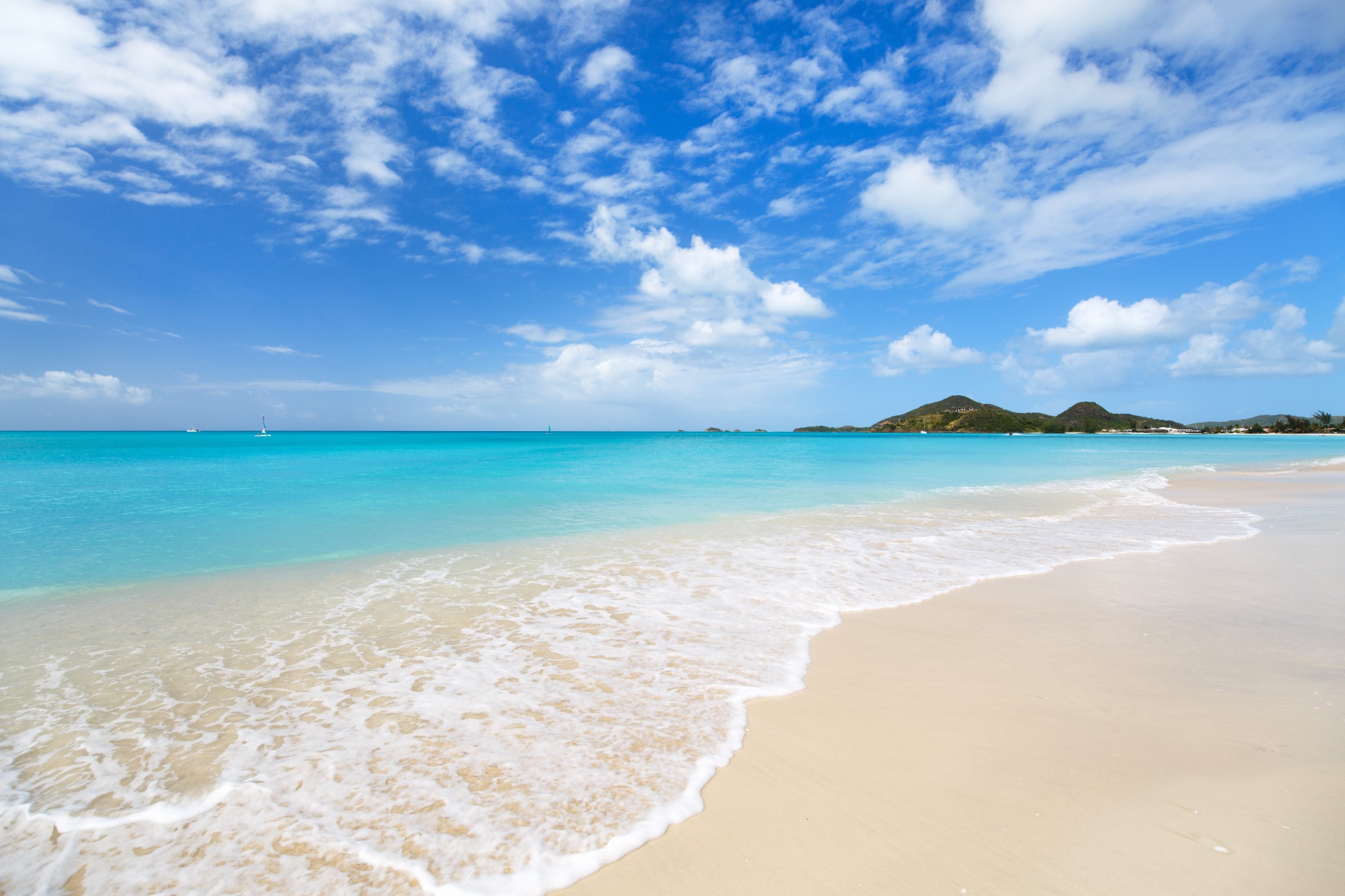 Idylliczna tropikalna plaża z białym piaskiem, turkusową wodą oceanu i błękitnym niebem na wyspie Antigua na Karaibach